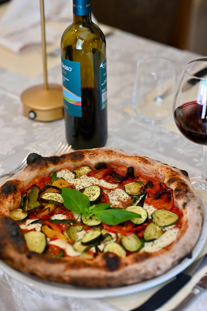 Pizza aux légumes, basilic, vin rouge à table