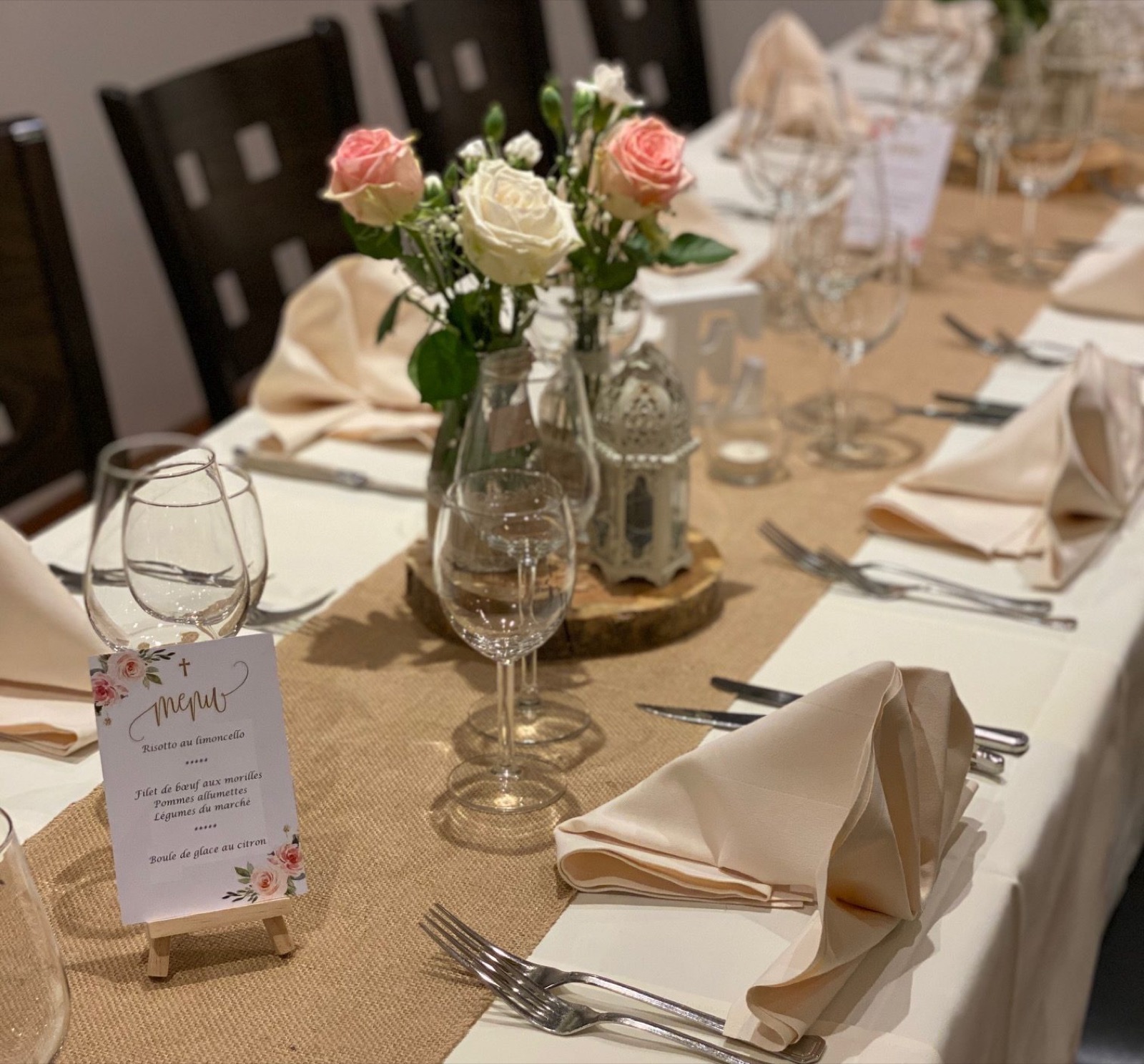 Table de banquet dressée pour un baptême : roses, menus, chemin de table en toile de jute
