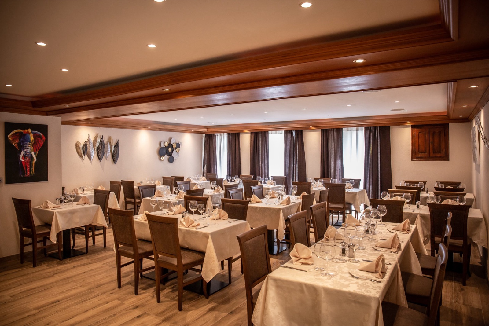 La grande salle du restaurant, tables dressées, plafond en bois