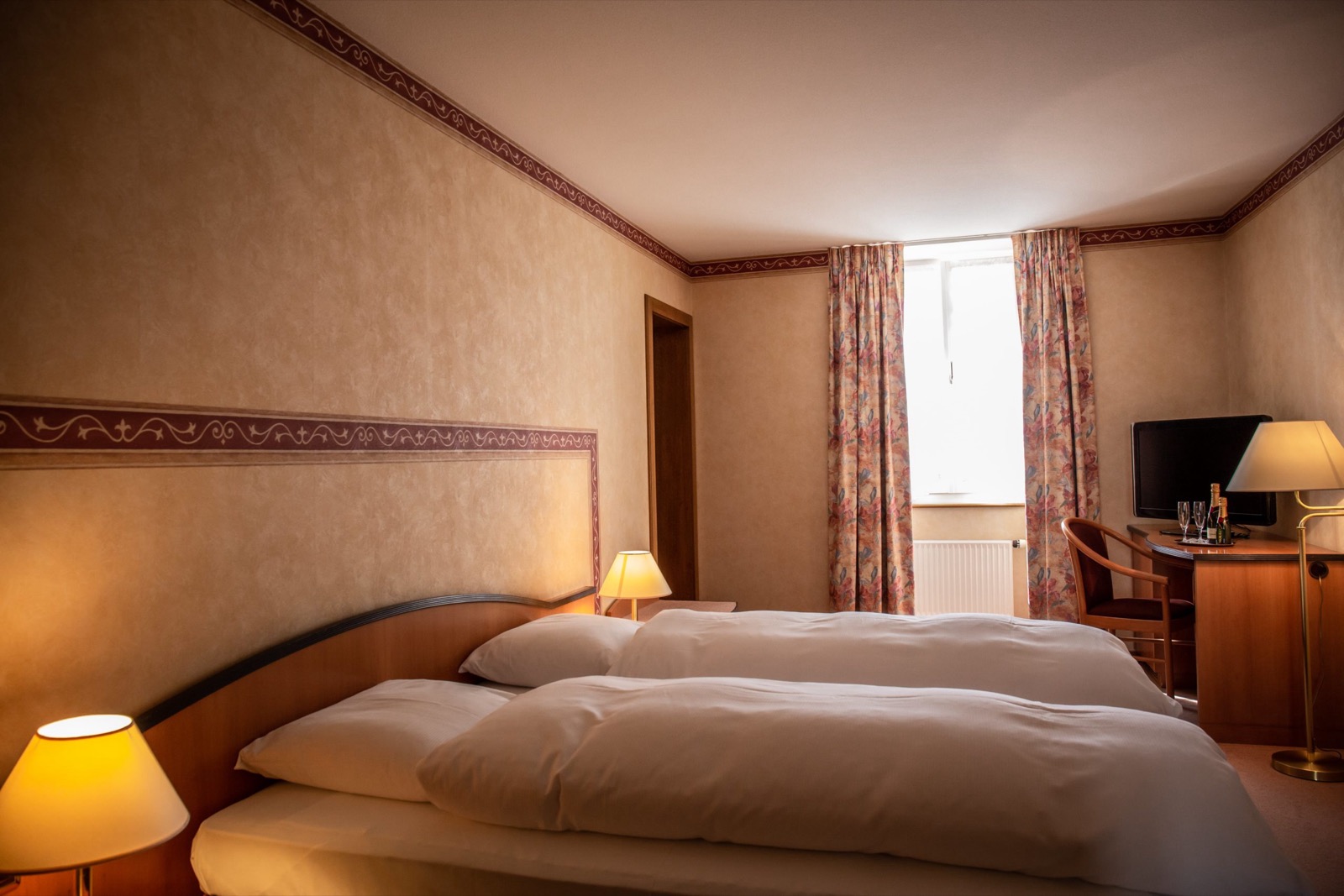 Chambre double de l’Hôtel des Alpes, lits jumeaux, bureau et télévision